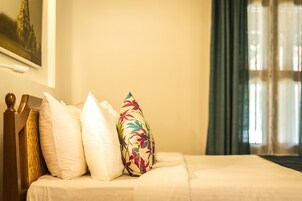 Una cama bien hecha con ropa de cama blanca y una almohada con motivos florales.