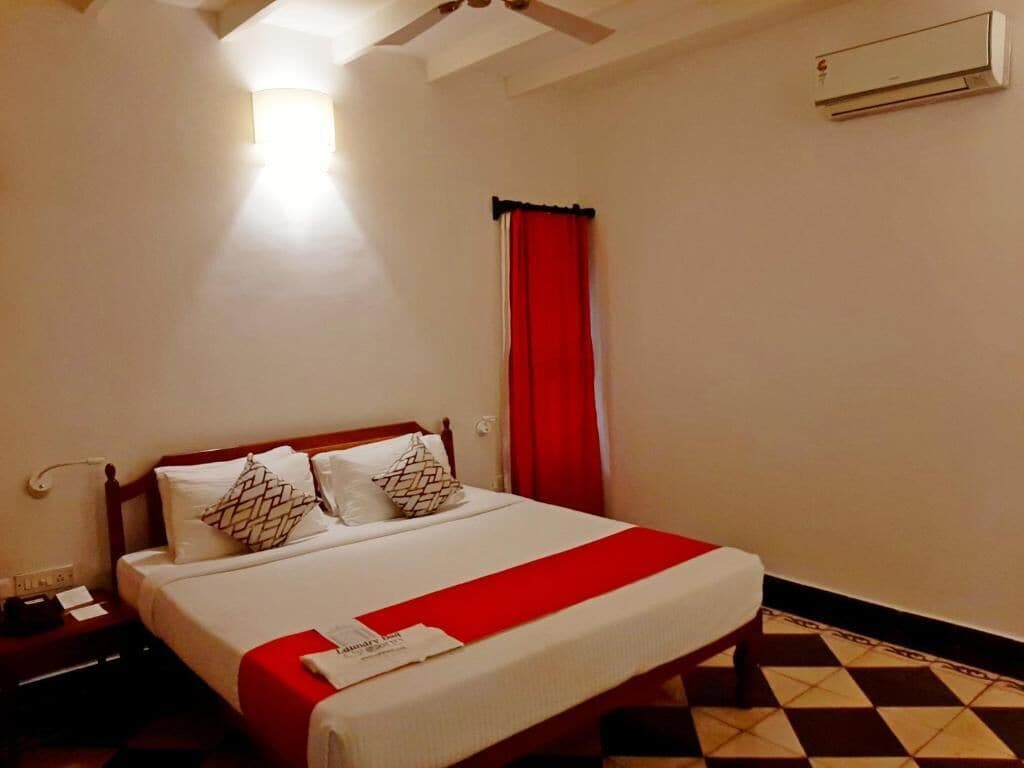 A hotel room with a bed, a nightstand, a red curtain, and a ceiling fan.