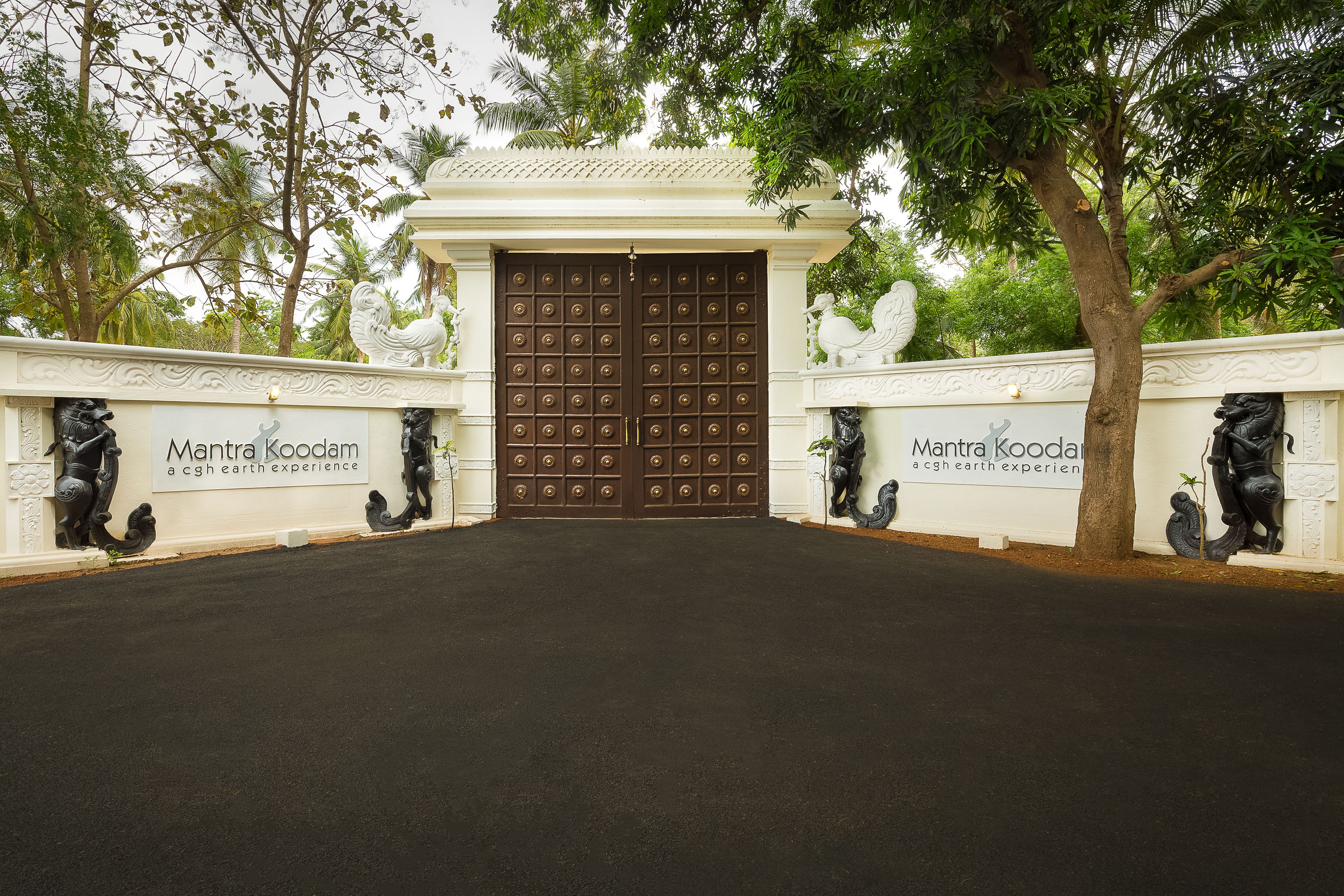 Un'imponente porta d'ingresso decorata con una targa che riporta la scritta "Mantra Koodam".