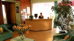 A reception area with a wooden desk, a green sofa, and a vase of flowers.