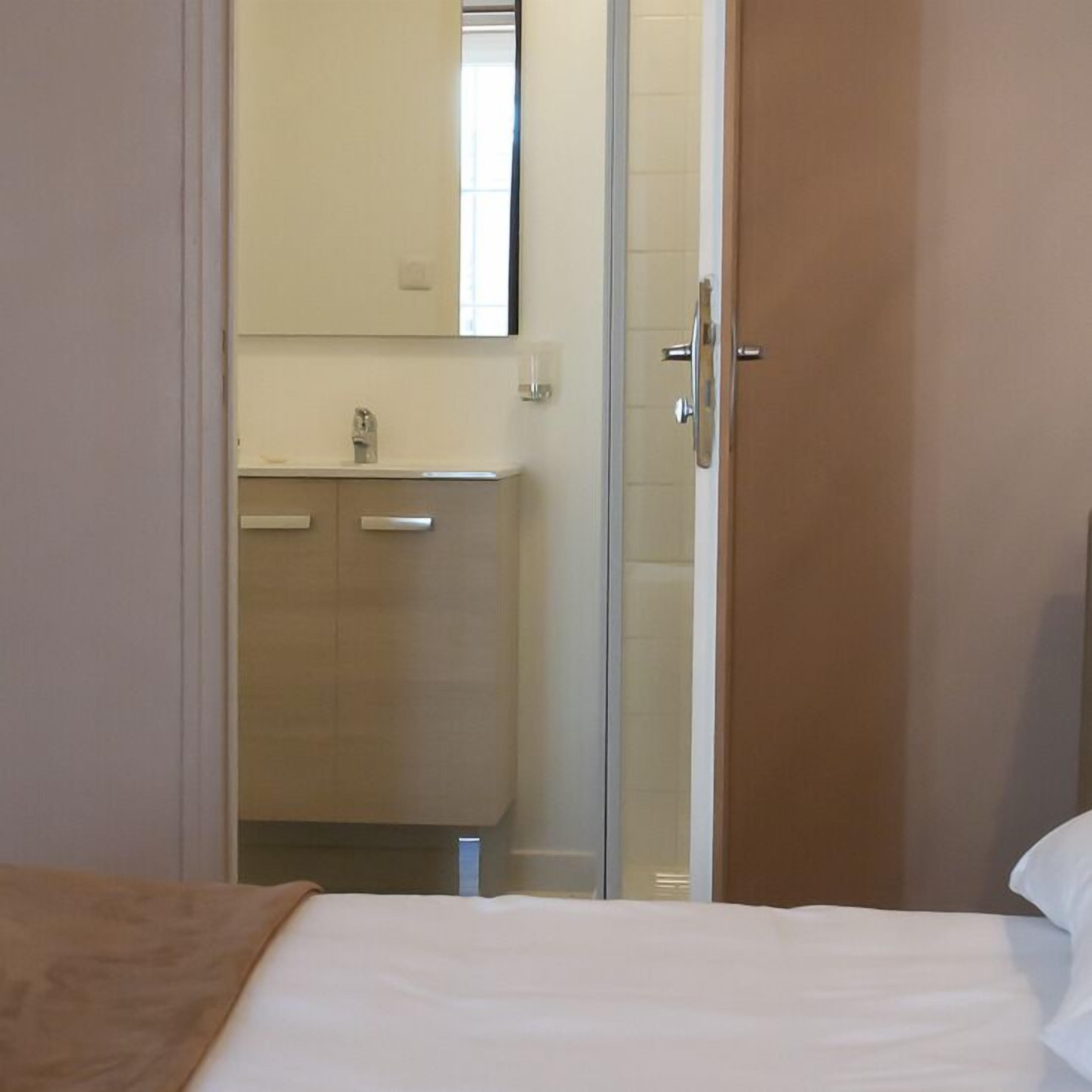 Una habitación de hotel con cama, baño con ducha y puerta de madera.