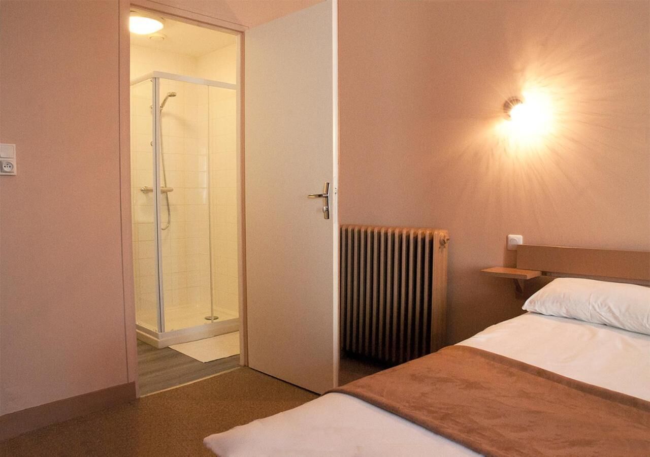 Quarto de hotel com cama, mesa de cabeceira, radiador e área de duche.