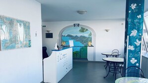 Un espace d’accueil comprenant un comptoir, des chaises, une carte et une fresque murale.