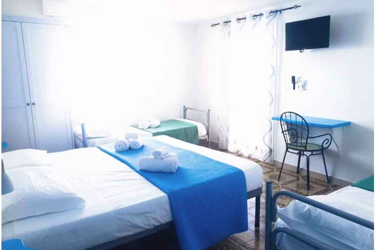 Ein Hotelzimmer mit zwei Betten, einem Schreibtisch und einem Stuhl.
