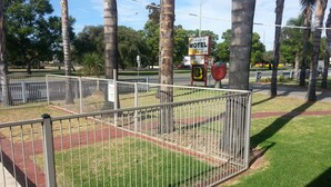 A fenced outdoor area with a sign for Sunraysiaia Motel, indicating it offers holiday apartments and a swimming pool. - Sunraysia Motel & Holiday Apartments (Mildura)