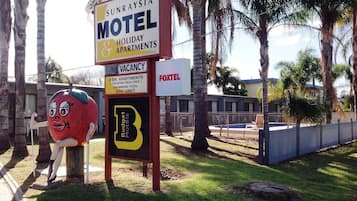 A motel sign with a cartoon character, indicating a vacancy for 2-bedroom apartments with amenities like a swimming pool and spa unit.