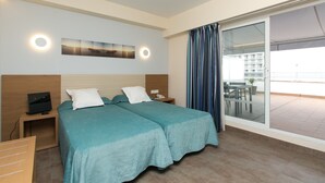 Une chambre d’hôtel avec deux lits, une télévision, un bureau et un balcon avec vue.