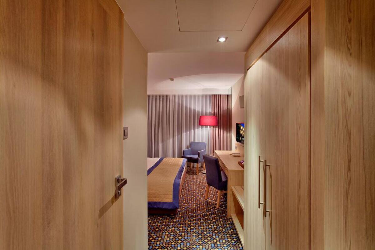 Ein Hotelzimmer mit einem Bett, einem Schreibtisch, einem Stuhl, einer Lampe und einem Kleiderschrank.