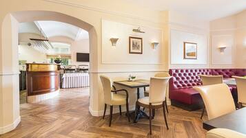 A dining area with a wooden herringbone floor, a buffet station, and a red upholstered bench.