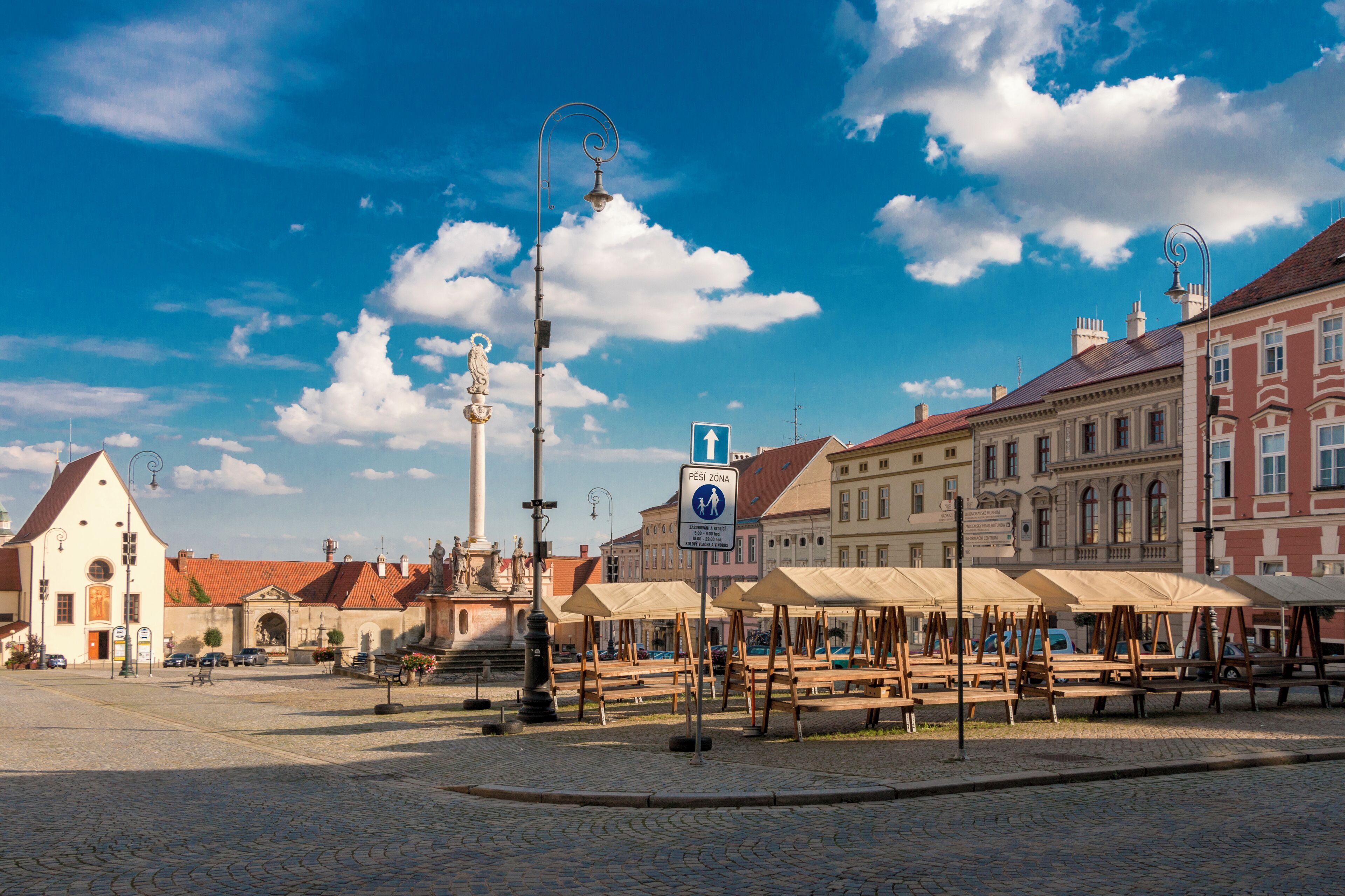 A cobblestone square with benches, a statue, and historic buildings.