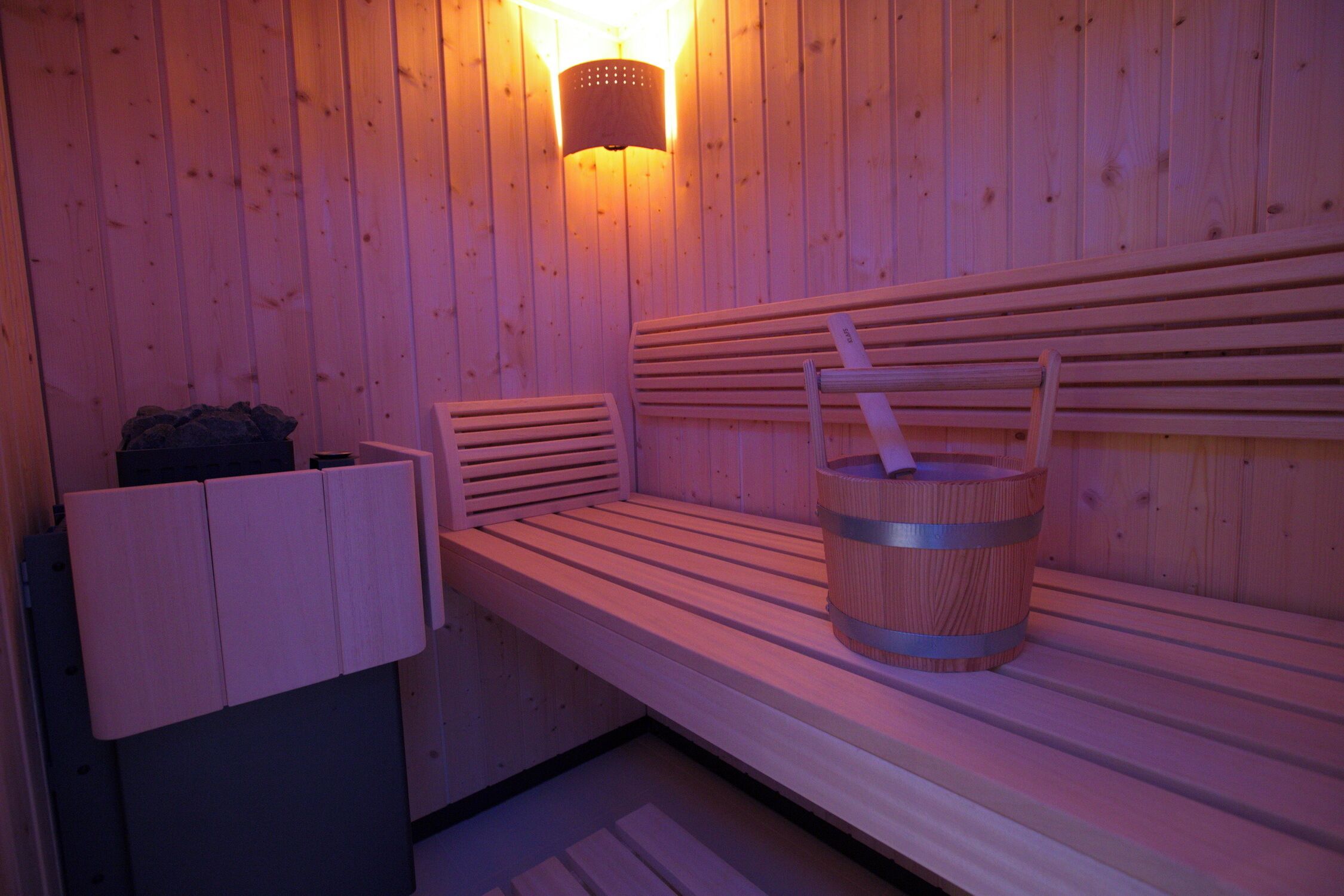 Una sauna de madera con bancos y un cubo.