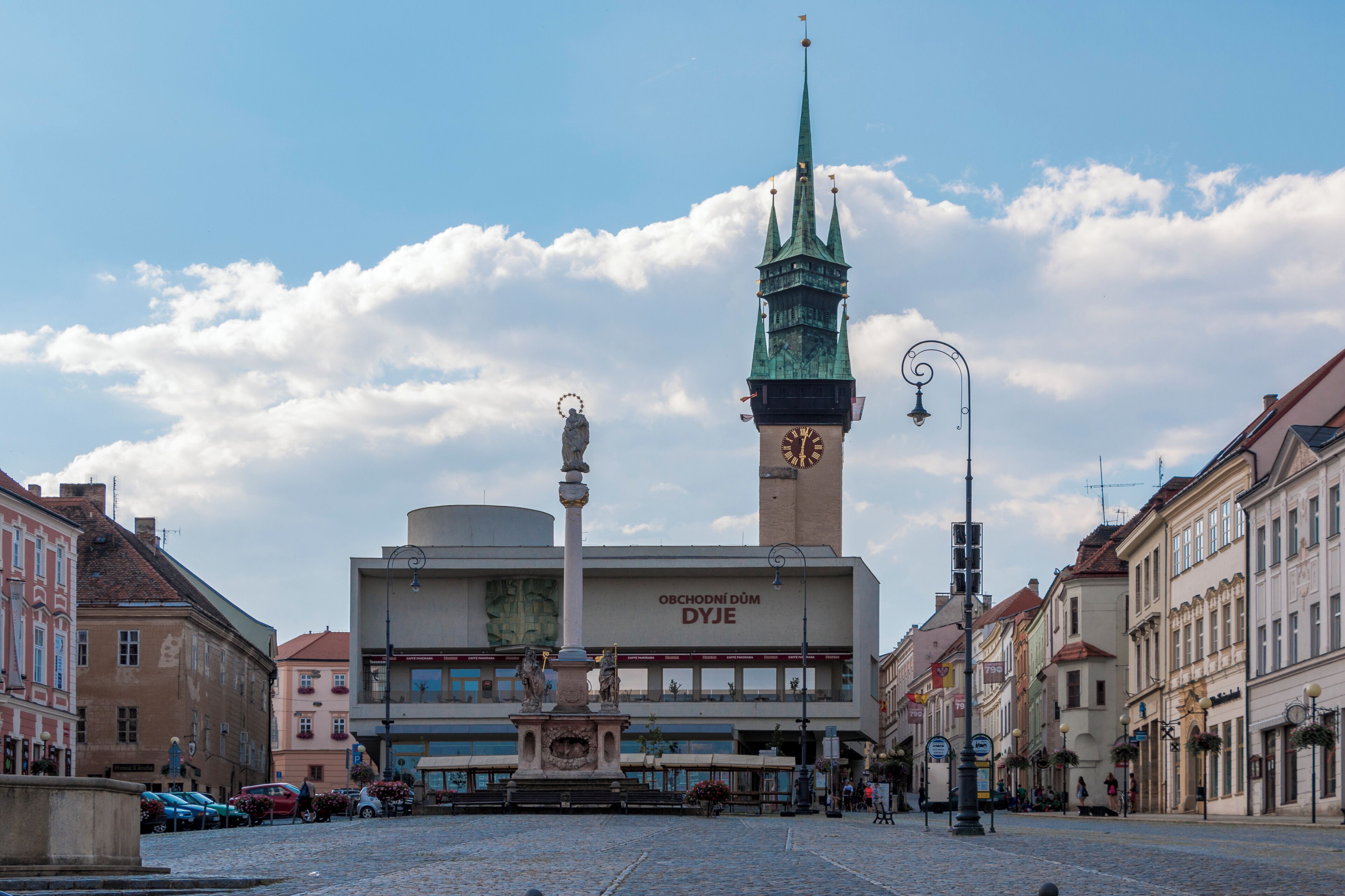 A historic building with a clock tower, a statue, and a cobblestone street.