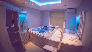 Un baño moderno con una bañera amplia, cabina de ducha con mampara de cristal y zona de estar con toallas.