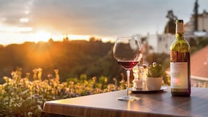 Una botella de vino y una copa sobre una mesa, con vista al atardecer.
