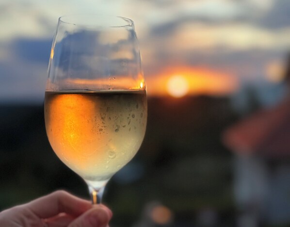 Una copa de vino blanco frente a un atardecer.