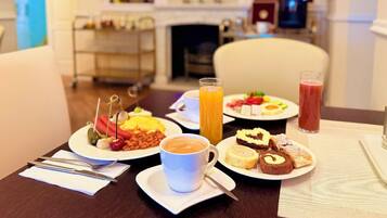 A breakfast setting with plates of food, a coffee cup, and a glass of orange juice.