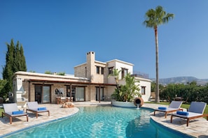 A modern villa with a swimming pool, outdoor seating, and a view of the mountains. - Amera Villas (Pegeia)