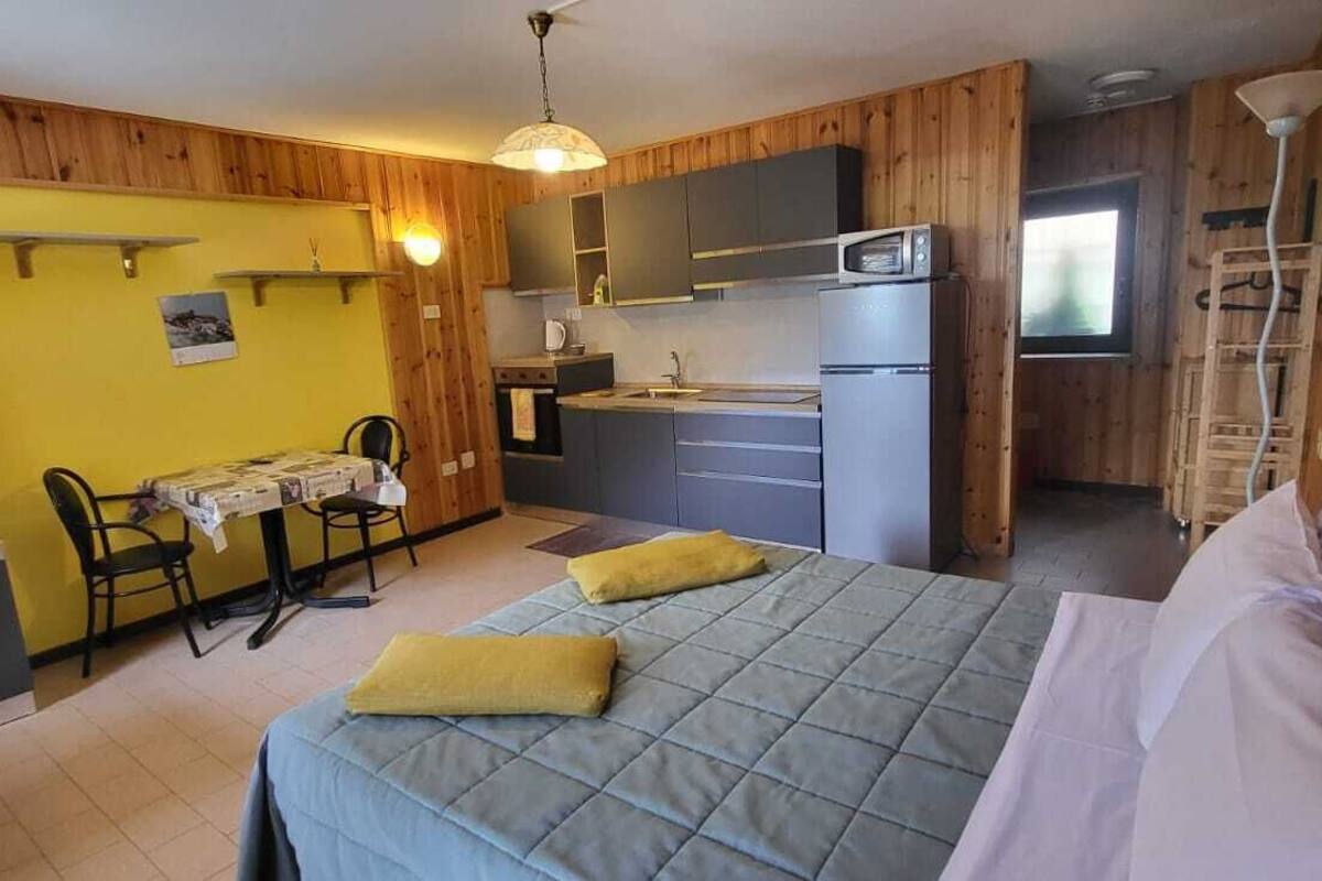 A compact room with a bed, a small kitchenette, a dining area, and a television.