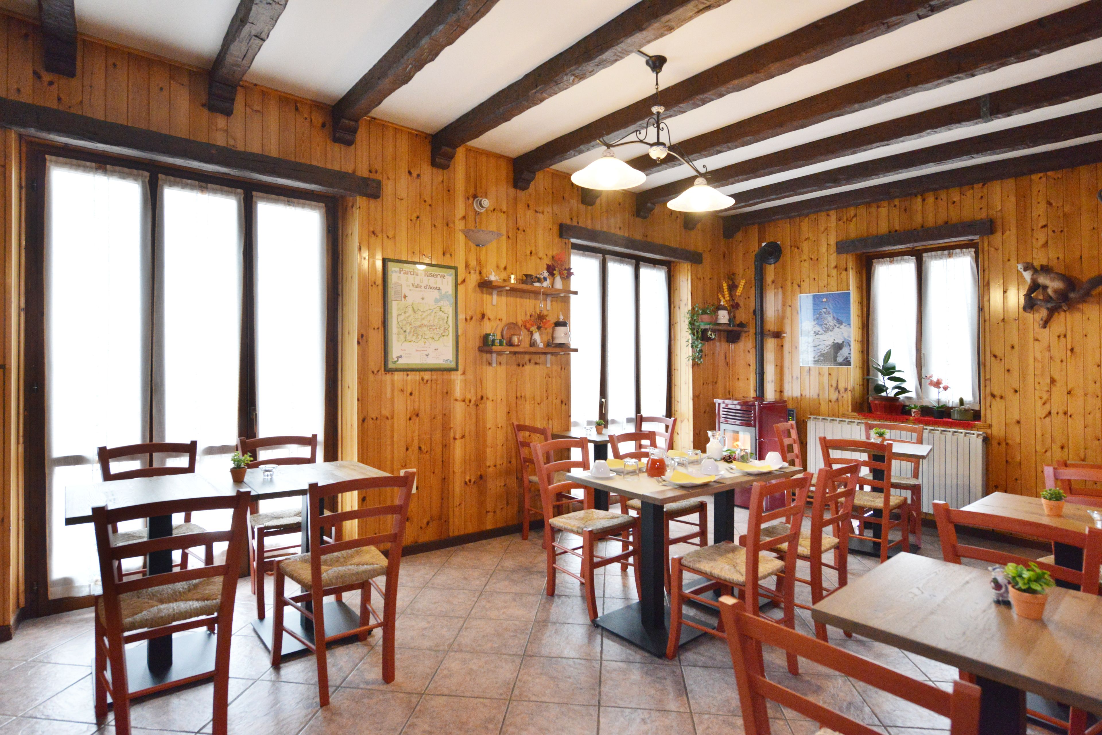 Un interno in legno con diversi tavoli e sedie, ampie finestre e una ventola a soffitto.