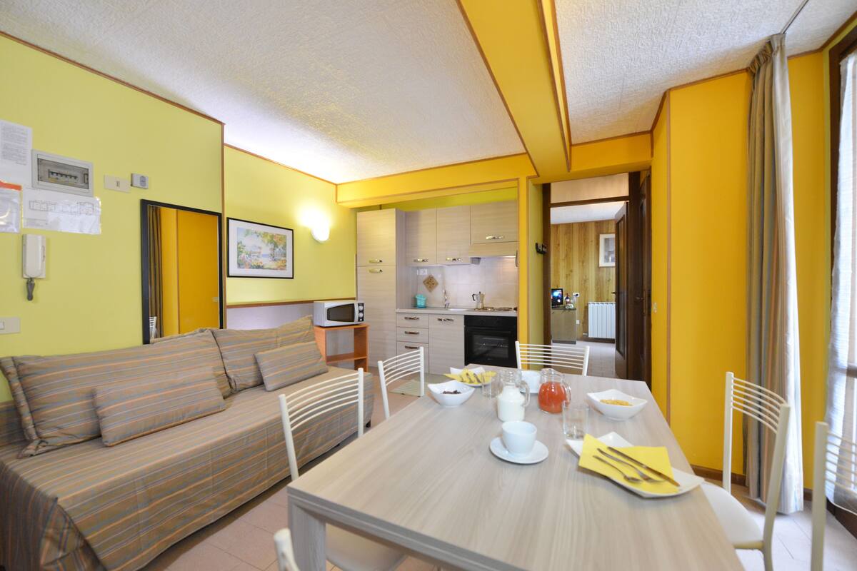 A compact living space with a sofa, dining table, and kitchen area.