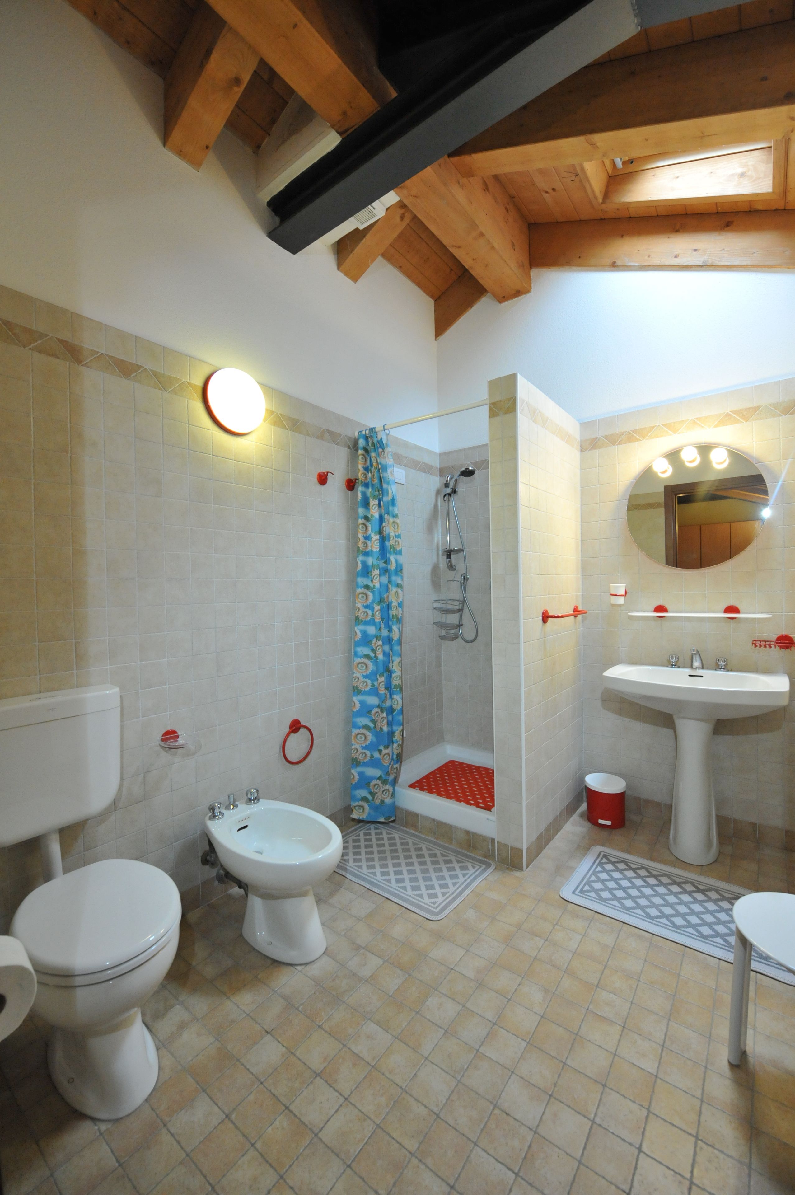 Une salle de bain équipée d’une douche, de toilettes, d’un bidet, d’un lavabo et d’un miroir.
