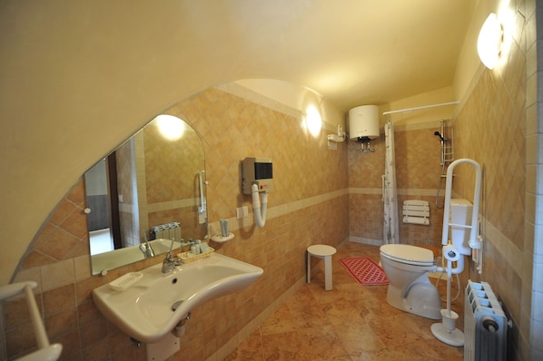 A bathroom with a sink, toilet, shower, and a small step stool.
