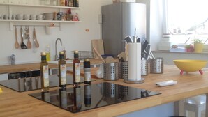 Une cuisine dotée d’un plan de travail en bois, de casseroles en acier inoxydable, d’un réfrigérateur et de divers ustensiles de cuisine.
