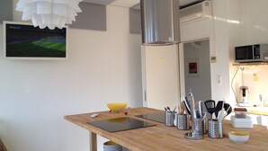Une cuisine moderne avec une table en bois, des appareils en acier inoxydable et une grande décoration florale en papier blanc.