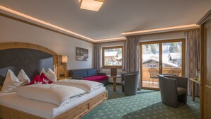 Une chambre d’hôtel avec un grand lit, un canapé, une petite table et un balcon avec des chaises.