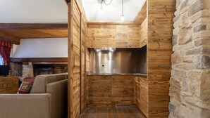 A compact kitchen with wooden cabinetry and a stone accent wall. - Residence Le Grand Chalet (Courmayeur)