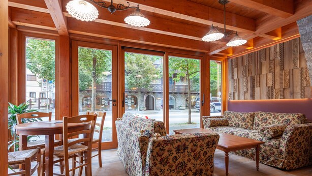 A wooden interior with a dining table, chairs, sofas, and a patterned wall. - Residence Le Grand Chalet (Courmayeur)