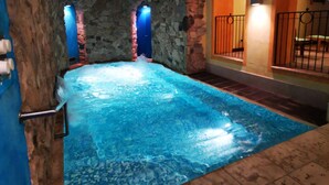 An indoor swimming pool with stone walls and a tiled floor. - Residence Le Grand Chalet (Courmayeur)