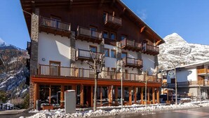 A multi-story hotel with balconies, large windows, and a mountain backdrop. - Residence Le Grand Chalet (Courmayeur)
