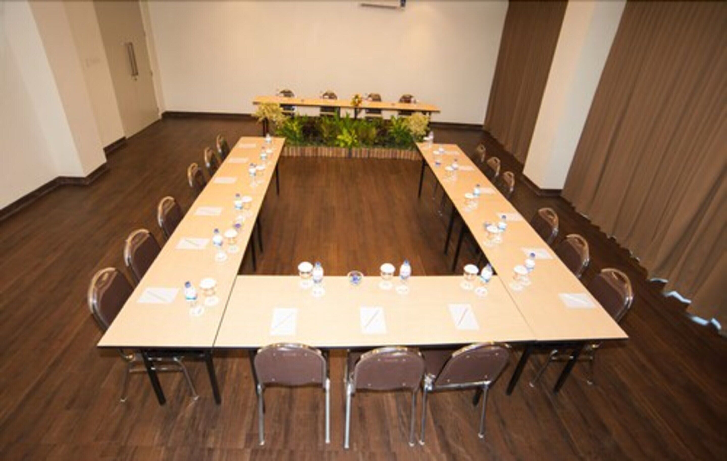 A conference room with a long table, chairs, and a small plant in the center.