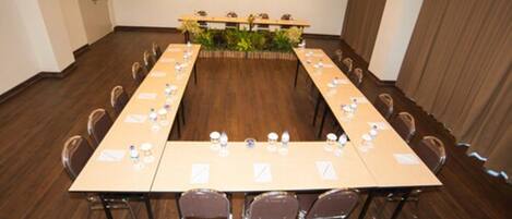 A conference room with a long table, chairs, and a small plant in the center.