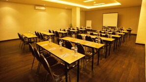 A conference room with multiple tables and chairs, equipped with water bottles and notepads. - idoop Hotel Lombok (Mataram)