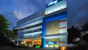A multi-story hotel with a prominent sign, multiple balconies, and a well-lit entrance. - idoop Hotel Lombok (Mataram)