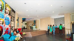 A hotel lobby with colorful artwork on the walls, a reception desk, and seating areas. - idoop Hotel Lombok (Mataram)