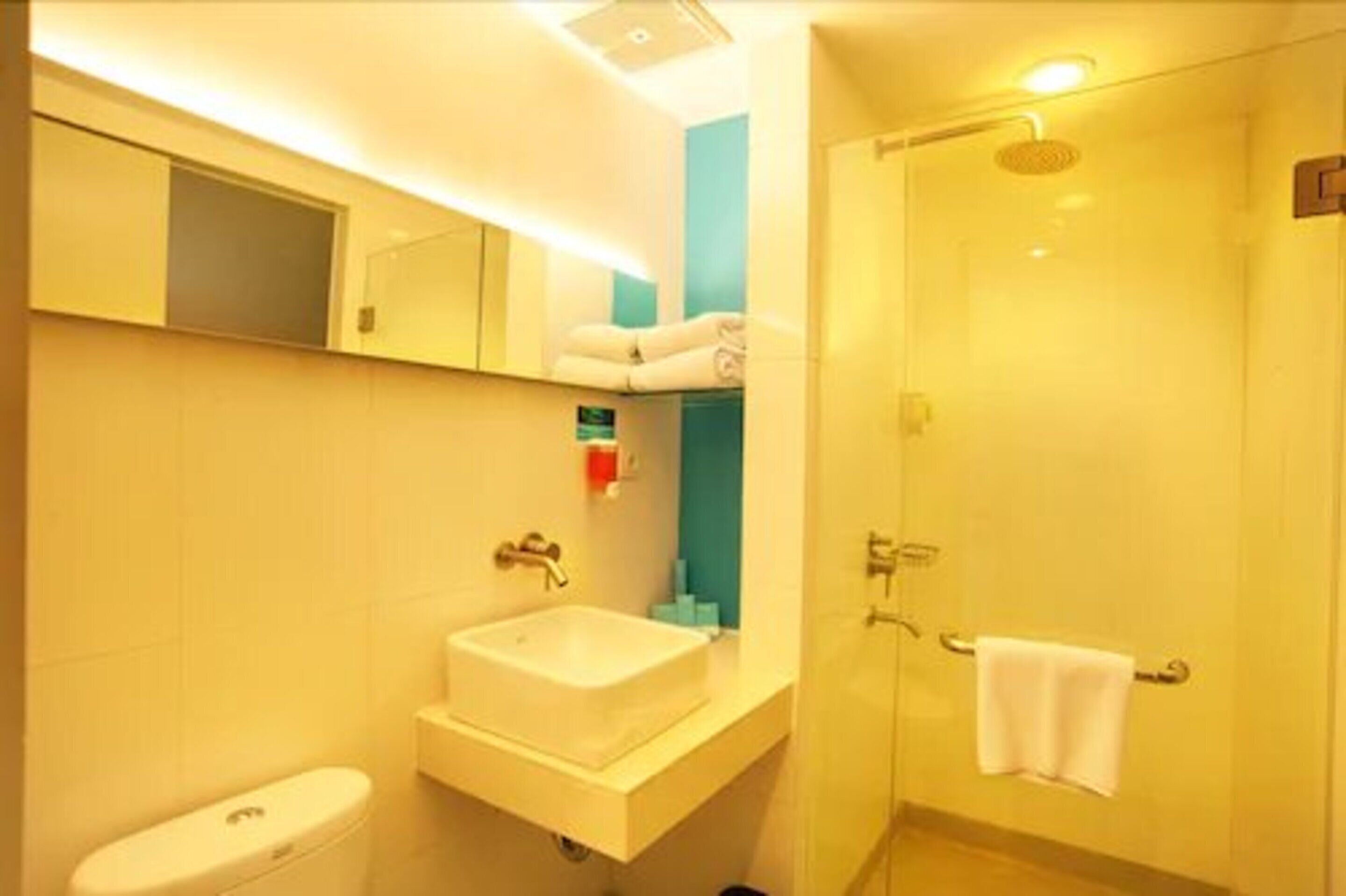 A bathroom with a white sink, a mirror, a towel rack, and a shower area.