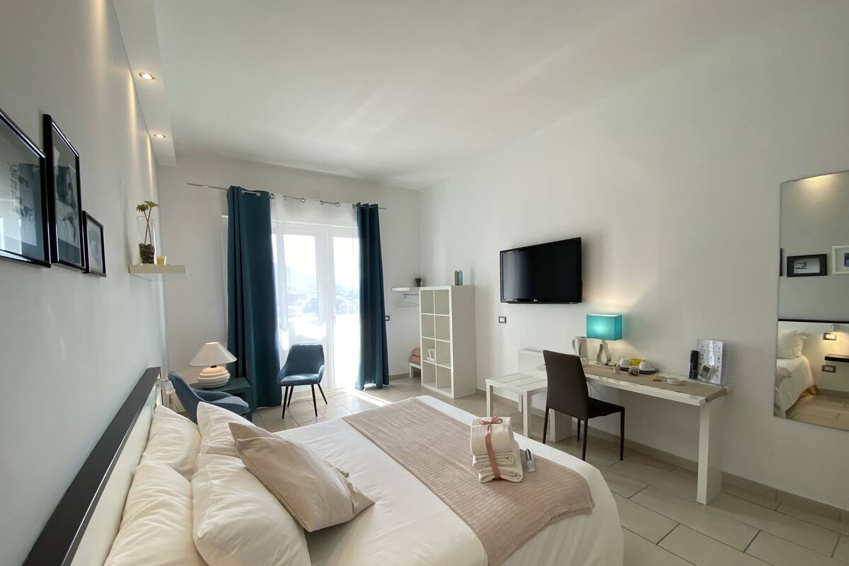 Una habitación de hotel moderna con una cama, escritorio, silla y televisión montada en la pared.