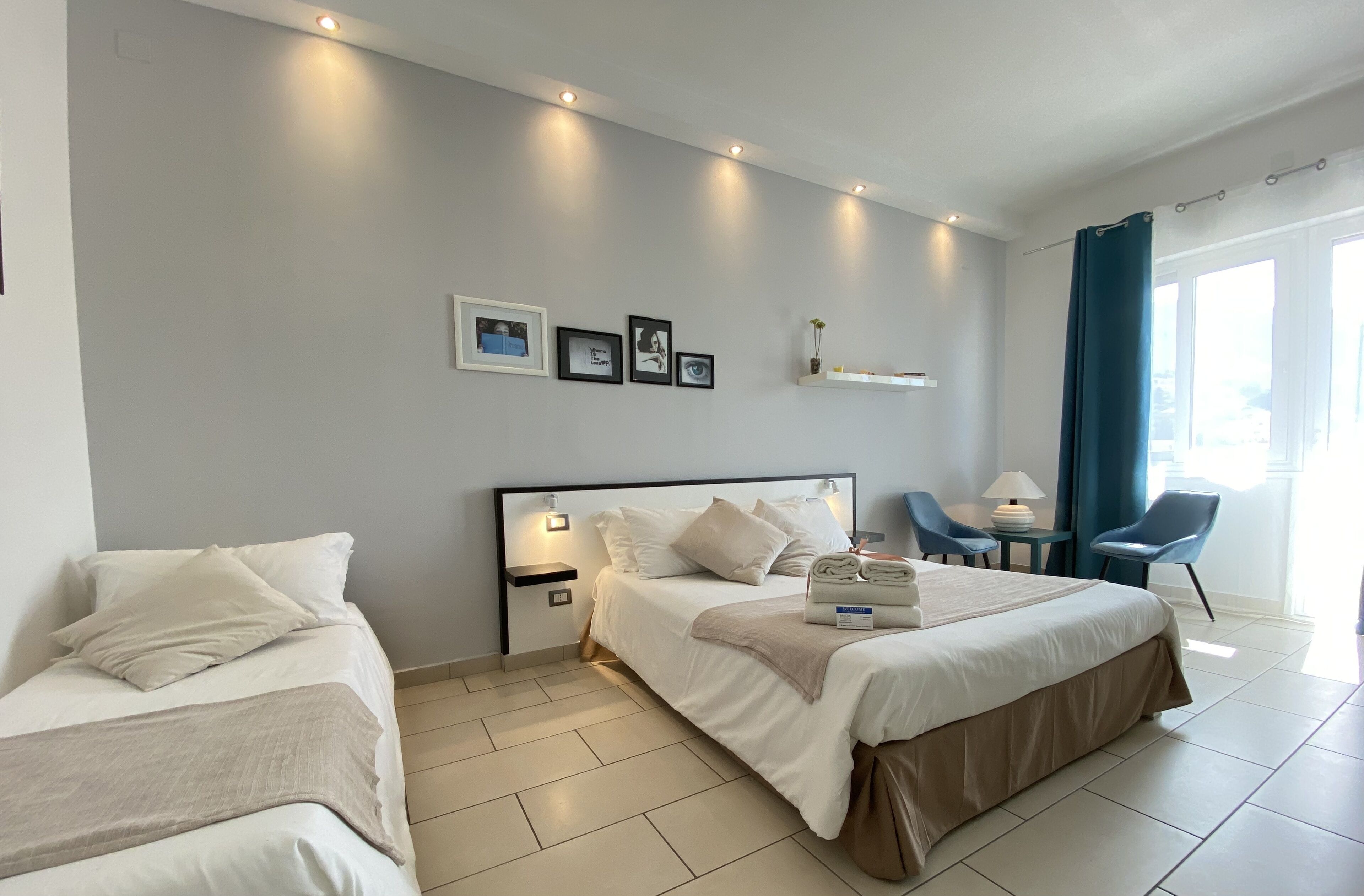 Une chambre d’hôtel avec deux lits, un bureau, une chaise et une fenêtre avec des rideaux.