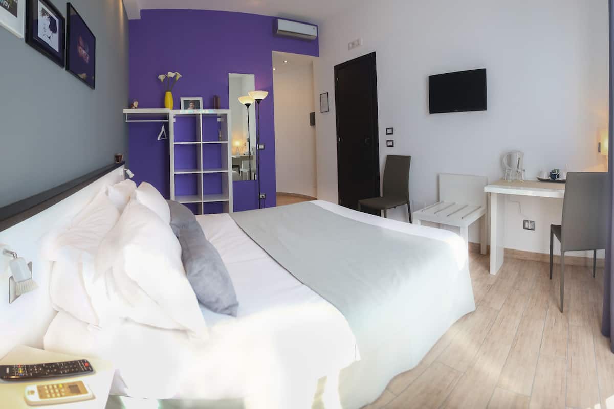 Una habitación de hotel moderna con una cama grande, un escritorio, una silla y un televisor.
