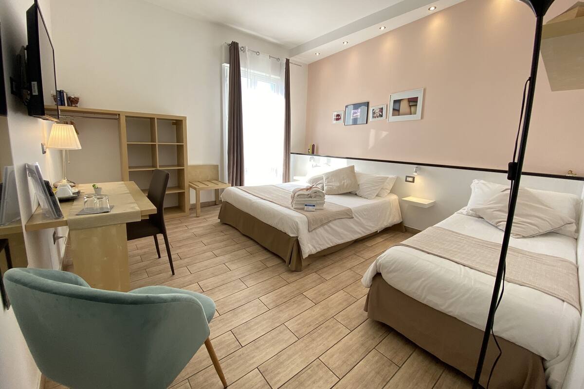 Una habitación de hotel con dos camas, un escritorio, una silla, un televisor y una lámpara.
