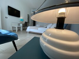 Una habitación de hotel moderna con una cama, un escritorio, una silla, un televisor de pantalla plana y una lámpara de techo.