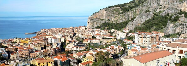 A coastal town with densely packed buildings, a prominent cliff, and a clear view of the sea.