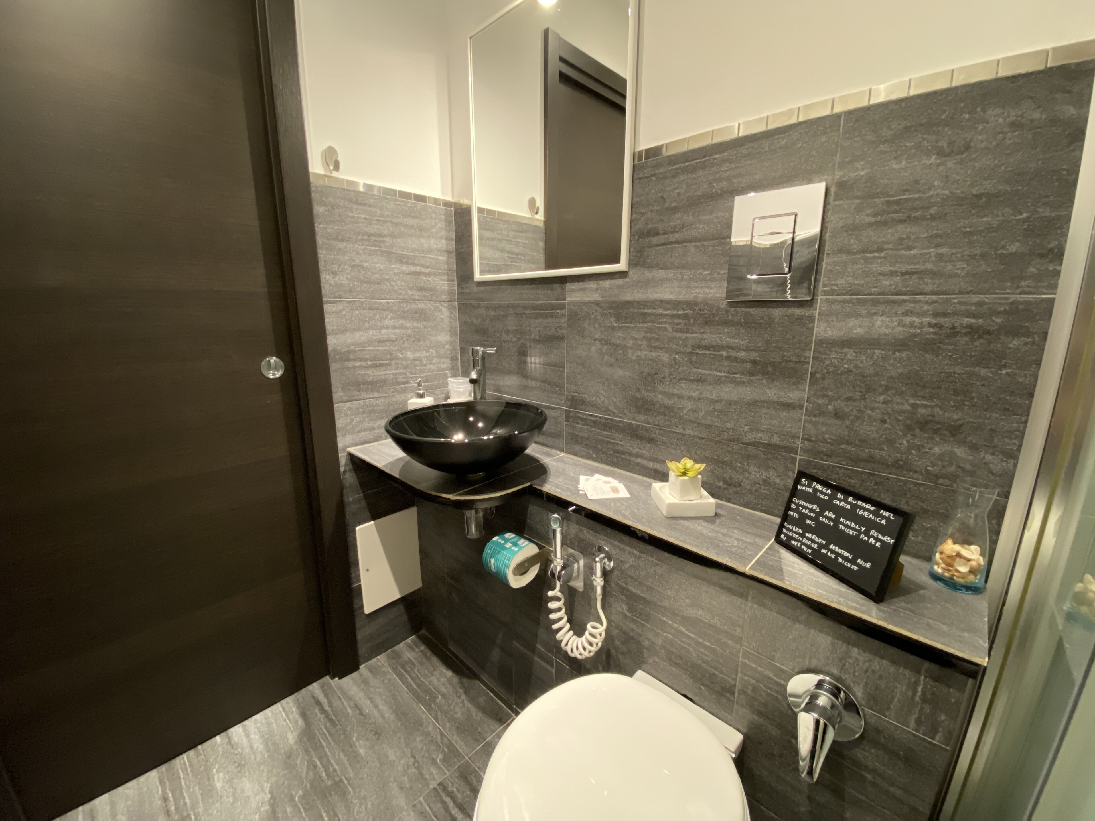 A modern bathroom with a black vessel sink, a toilet, and a mirror.
