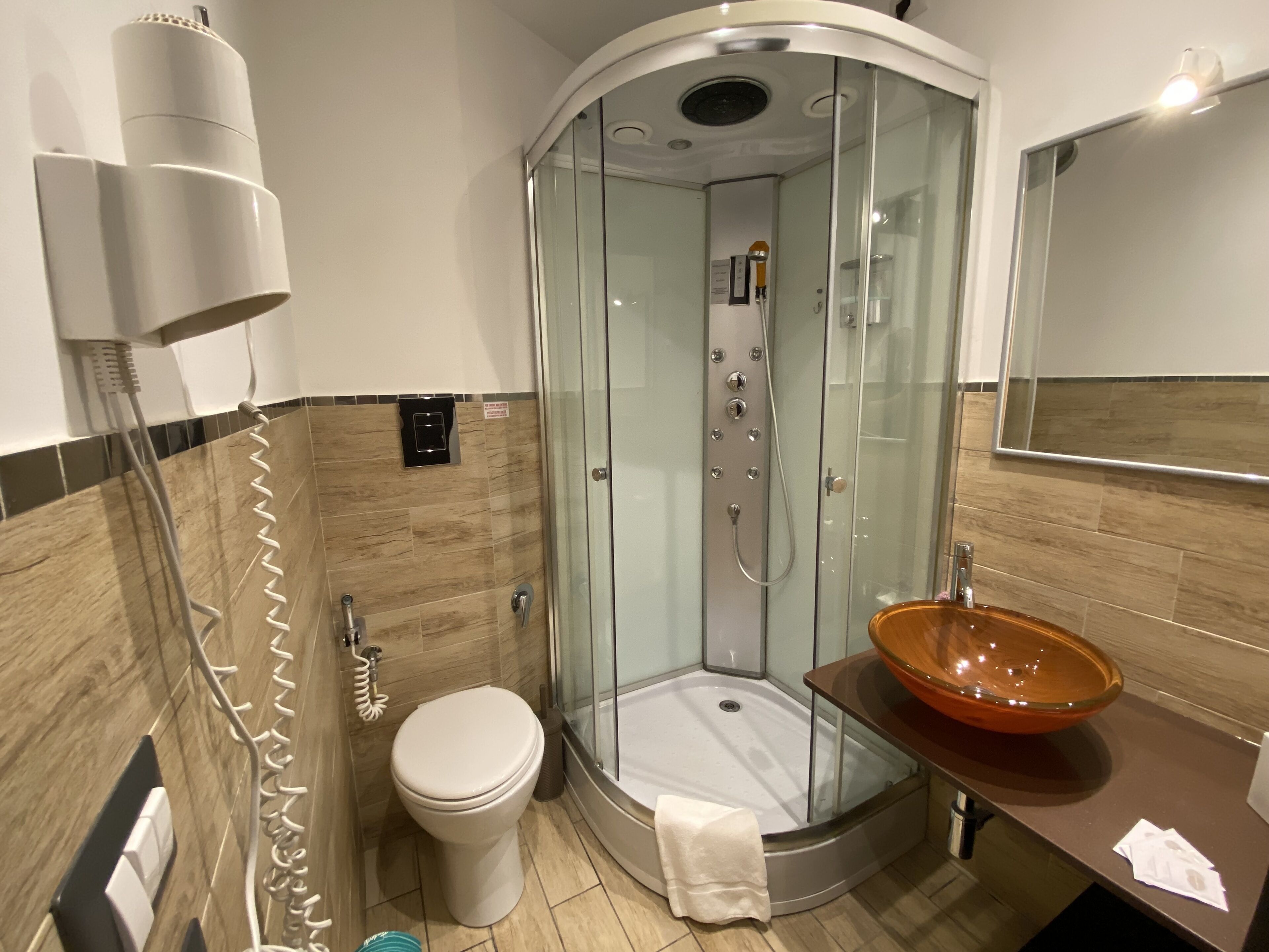 A modern bathroom with a glass-enclosed shower, a toilet, and a vanity with a large bowl sink.