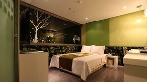 Ein modernes Hotelzimmer mit einem großen Bett, einem Nachttisch, einem Spiegel und einem Fenster mit Baum-Motiv.
