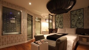 Ein modernes Hotelzimmer mit einem großen Bett, einer Sitzecke mit einer Zeitschrift, einem Fernseher und einem großen Fenster mit Blick auf die Stadt.