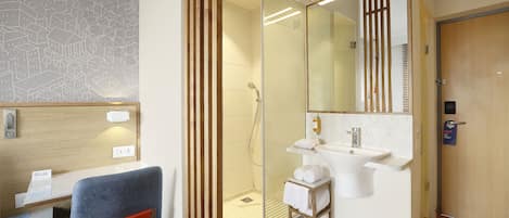 A modern bathroom with a glass-enclosed shower, a white sink, and a mirror.